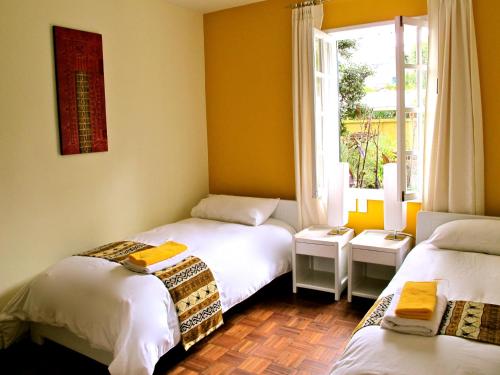 Habitación con 2 camas individuales y ventana. en Hotel Cayman, en Quito