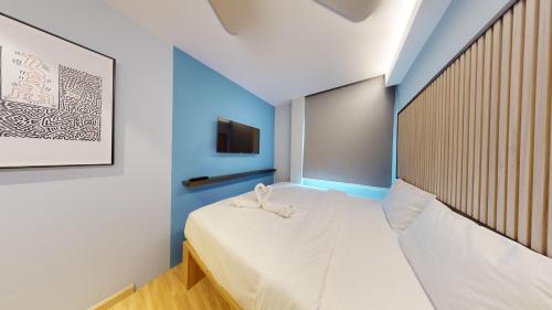 a bedroom with a white bed with a blue accent wall at Blue Lagoon At Bandar Sunway in Petaling Jaya