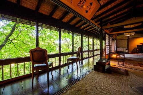 a room with two chairs and a balcony with windows at 川魚・山菜料理　和田屋 in Hakusan