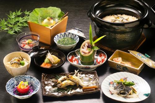 a table with plates of food and a pot of food at 川魚・山菜料理　和田屋 in Hakusan