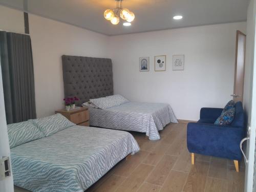 Pokój z 2 łóżkami i niebieskim krzesłem w obiekcie exclusivo apartamento w Quibdó
