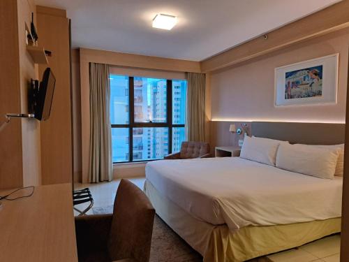 um quarto de hotel com uma cama e uma grande janela em BSB STAY Flats particulares - CULLINAN em Brasília