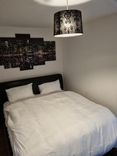 a bedroom with a white bed and a chandelier at C'S LUXURIOUS Flat in Barking