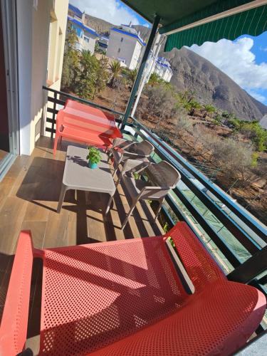 a balcony with red chairs and a table with a view at Cristimar H23 big pool, 3 bedroom and 3 baths in Los Cristianos