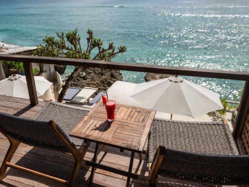 a table and chairs on a balcony with the ocean at Rock'n Reef in Uluwatu