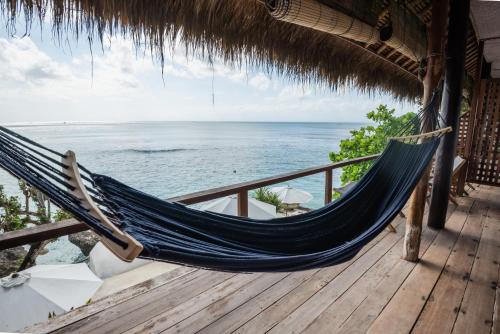 a hammock on a deck with a view of the ocean at Rock'n Reef in Uluwatu