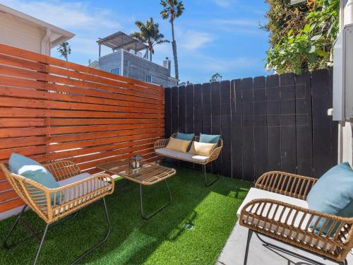 a patio with two chairs and a table and a fence at Beach Bungalow Perfection - Private Patios, BBQ walk2beach & Pet Friendly! in San Diego