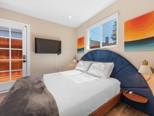 a bedroom with a large bed with a blue headboard at Beach Bungalow Perfection - Private Patios, BBQ walk2beach & Pet Friendly! in San Diego