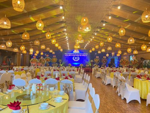 un salón de banquetes con mesas blancas, sillas y luces en Thung Nham Resort, en Ninh Binh