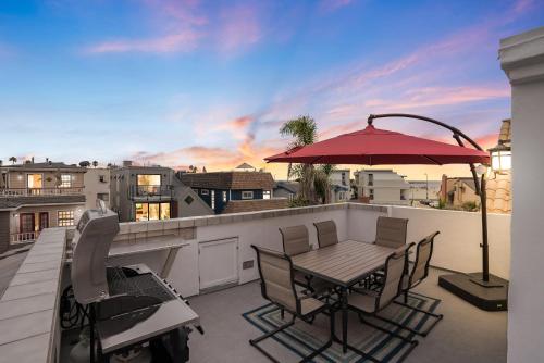 a patio with a table and an umbrella on a balcony at Beach Perfection - Ocean Views, Parking, Pet Friendly & Steps2Sand in San Diego
