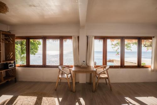 a living room with windows and a table and chairs at Rock'n Reef in Uluwatu