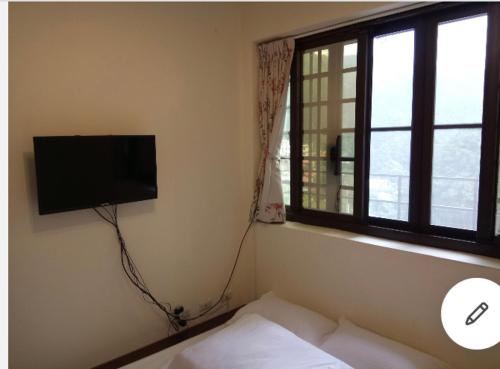 a bedroom with a bed and a television on the wall at 金蘭小築民宿 in Zhuqi