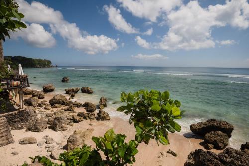 a beach with some rocks and the ocean at Rock'n Reef in Uluwatu
