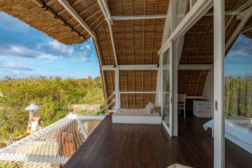 a room with a balcony with a view of the ocean at Villa Madu in Nusa Lembongan
