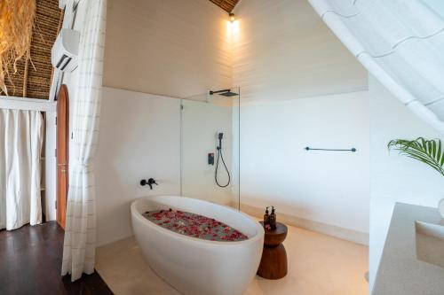 a bathroom with a large white tub with a shower at Villa Madu in Nusa Lembongan