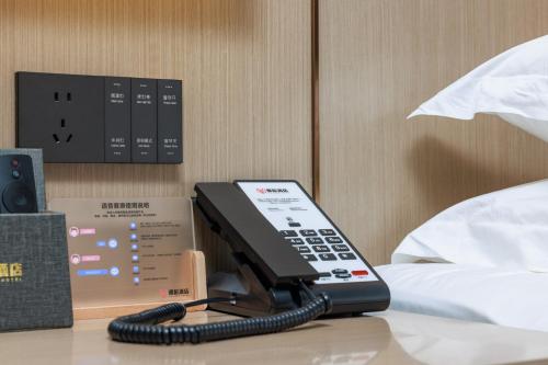 a phone sitting on a table next to a bed at Guangzhou Yachen Hotel in Guangzhou
