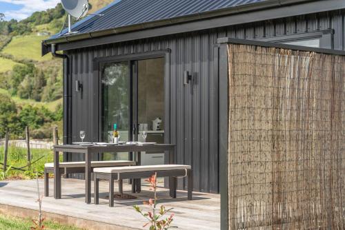 a black shed with a table and benches on a deck at Barn 944 - Big Omaha Holiday Home in Matakana