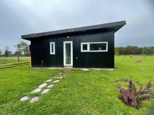 a black building with a door in a field at Casa en Lago Ranco in Ignao