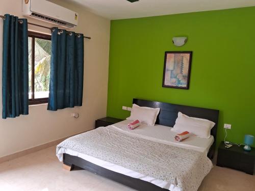 1 Schlafzimmer mit grünen Wänden und 1 Bett mit 2 Pinkippern in der Unterkunft Coconut Grove Holiday Apartment in Varca