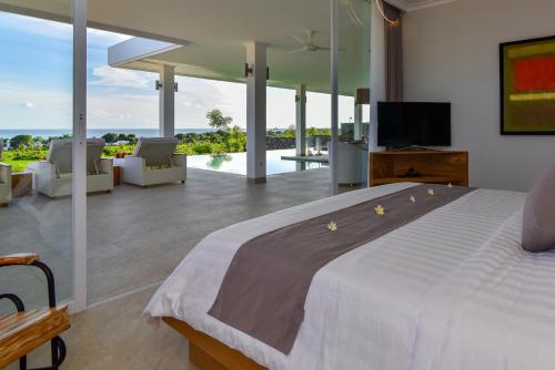 a bedroom with a large bed and a living room at Deep Blue Vila Managed by LBV in Singaraja