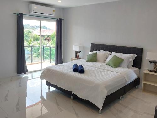 Un dormitorio con una cama grande con zapatos azules. en PR ROOM FOR RENT en Kamala Beach