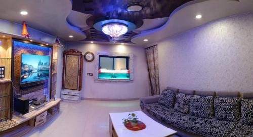 ein Wohnzimmer mit einem Sofa und einem TV in der Unterkunft Rudraksha Inn in Varanasi
