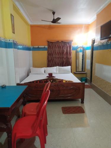 a bedroom with a bed and a table and a chair at PAYEL LODGE in Digha