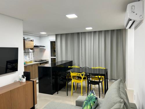 a dining room with a black table and yellow chairs at Apartamento perfeito em bairro nobre por insta @thiagojacomo in Goiânia