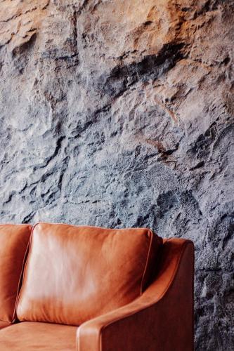 a brown leather couch in front of a stone wall at Urban Suites, Spectre Collection by Stellar ALV in Jelutong
