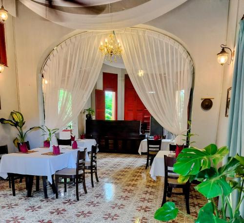 a restaurant with white tables and chairs and a piano at La Rivière d' Angkor Resort in Siem Reap
