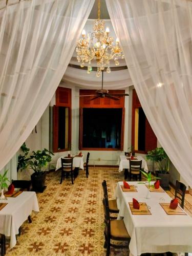 a restaurant with white tables and chairs and a chandelier at La Rivière d' Angkor Resort in Siem Reap