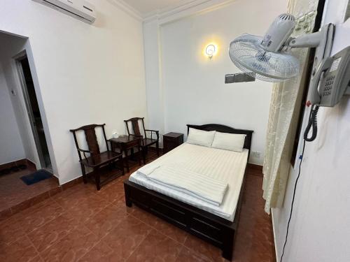 una camera con un letto in una stanza con sedie di Xuân An Hotel - 53 Nguyễn Thái Bình, Q. Tân Bình - by Bay Luxury ad Ho Chi Minh