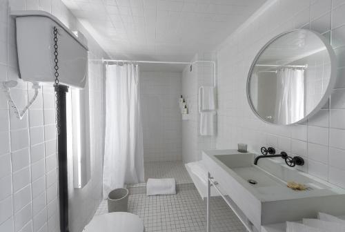 Baño blanco con lavabo y espejo en Hotel Carlota, en Ciudad de México