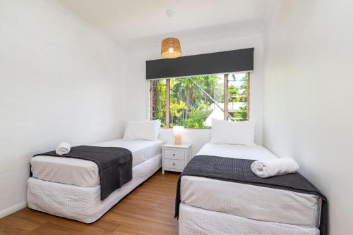 two beds in a room with a window at 5 Reef Terraces in Port Douglas