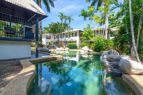 a swimming pool in front of a house with palm trees at 5 Reef Terraces in Port Douglas