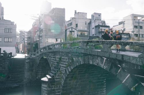 a group of people walking over a stone bridge at FAV LUX Nagasaki in Nagasaki