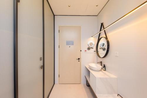 Shanghai Autoongo Bund Hotel في شانغهاي: حمام أبيض مع حوض ومرآة