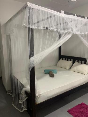 a bed with a canopy with white drapes at SONYA GARDEN View in Weligama