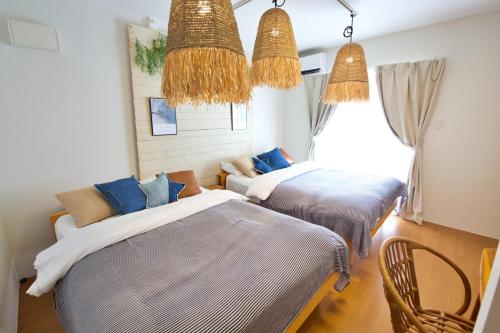 a bedroom with two beds and two chairs at クラリス大川 A号室 in Ishigaki Island