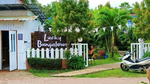 uma scooter estacionada em frente a um edifício com uma placa em LUCKY Bungalows Koh Mook em Ko Mook