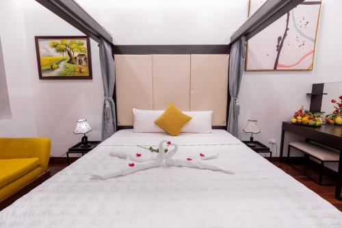 a bedroom with a bed with white sheets and a yellow couch at Hanoi Cozy Legend Hotel in Hanoi