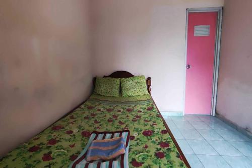 ein Schlafzimmer mit einem Bett mit einer grünen Decke und einer rosa Tür in der Unterkunft OYO 93395 Pondok Wisata Sekar Kemuning in Yogyakarta