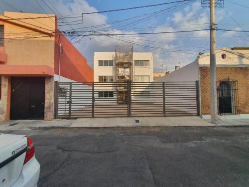 a building with a fence in front of a street at Departamento Amueblado in Puebla