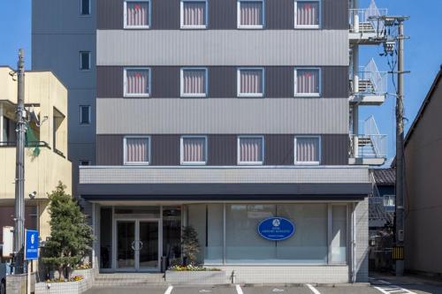 a tall building with a blue sign in front of it at Hotel Airport Komatsu in Komatsu