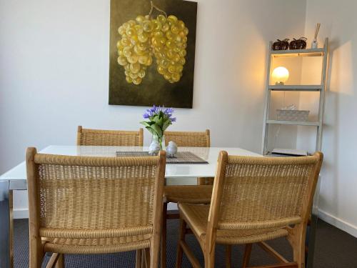 a dining room table with two chairs and a painting of grapes at Angaston Mews Apartments in Angaston