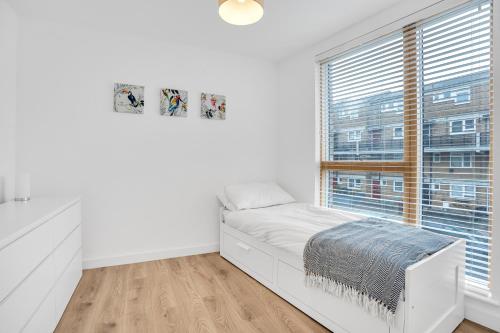 a white bedroom with a bed and a window at Spacious 2 bedroom apartment with balcony in London