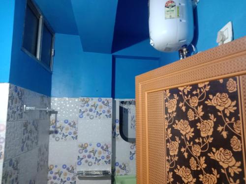 a bathroom with a shower with blue walls and a mirror at Goonkeshari Homestay in Ghum