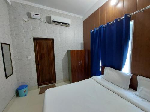 Saukari Palace في دهرادون: غرفة نوم بسرير وستارة زرقاء