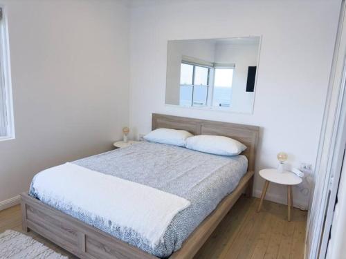 a white bedroom with a bed and a mirror at On The Esplanade - Close to beach & Cronulla mall with Aircon in Cronulla