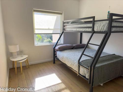 a bedroom with two bunk beds and a window at On The Esplanade - Close to beach & Cronulla mall with Aircon in Cronulla